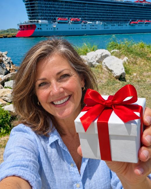 Mujer sonriente enseñando una caja de regalo con un lazo rojo, con un crucero atracado al fondo